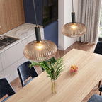 Two amber reeded glass pendants from Clérachic with black fittings hang over a light oak dining table, seen from above in a bright kitchen.