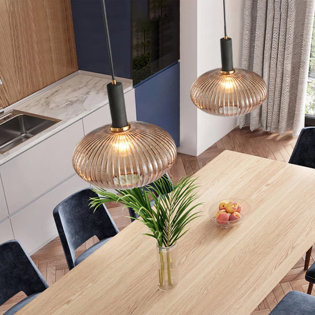 Two amber reeded glass pendants from Clérachic with black fittings hang over a light oak dining table, seen from above in a bright kitchen.