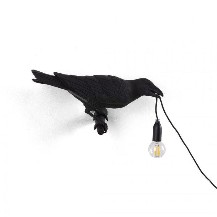 Its black resin counterpart from Clérachic mirrors the pose, wings spread, the warm bulb glowing on a white ground.