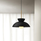 Black dome pendant from Clérachic lit with a round opal bulb, hung in front of floor-length white curtains.