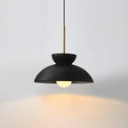 Black Clérachic pendant on a pale grey backdrop, its bulb throwing a warm pool of light onto the surface beneath.