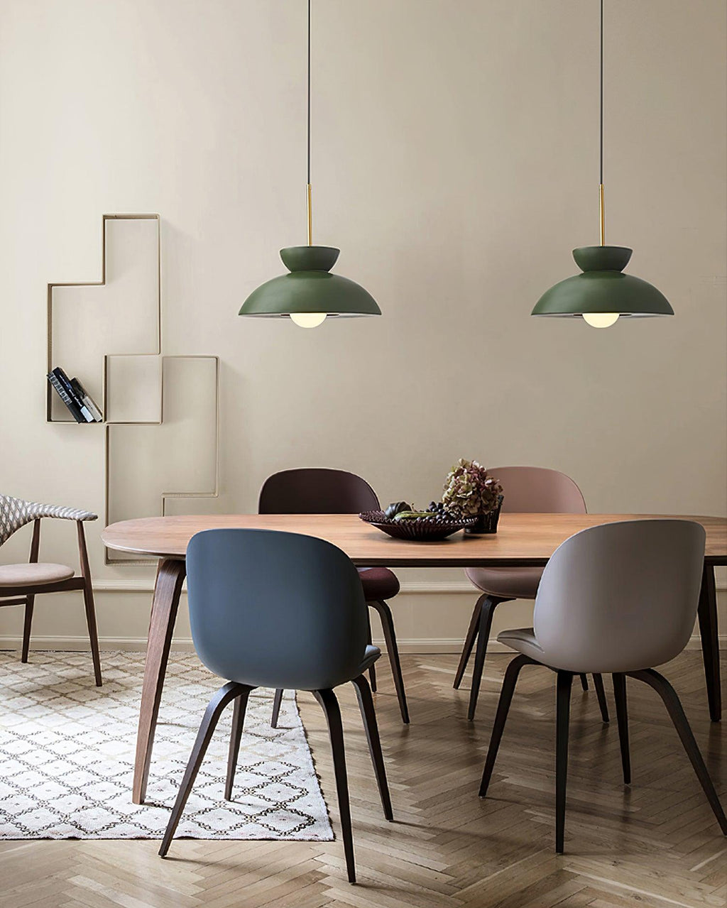 Two green dome pendants from Clérachic hang over a wooden dining table with blue and taupe moulded chairs.