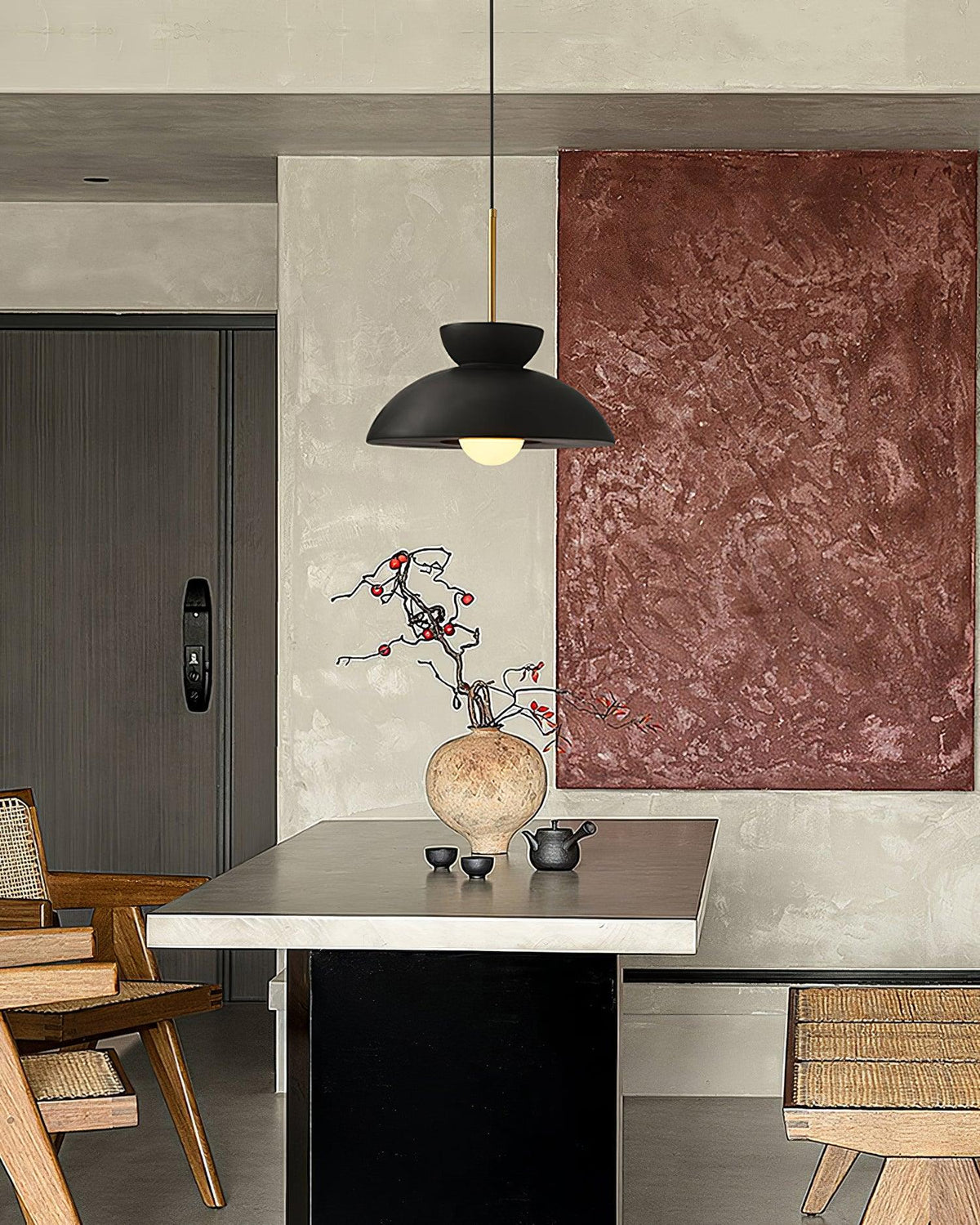 Black dome pendant from Clérachic in a dining area, beside a large rust-toned textured canvas and a stone-topped table.
