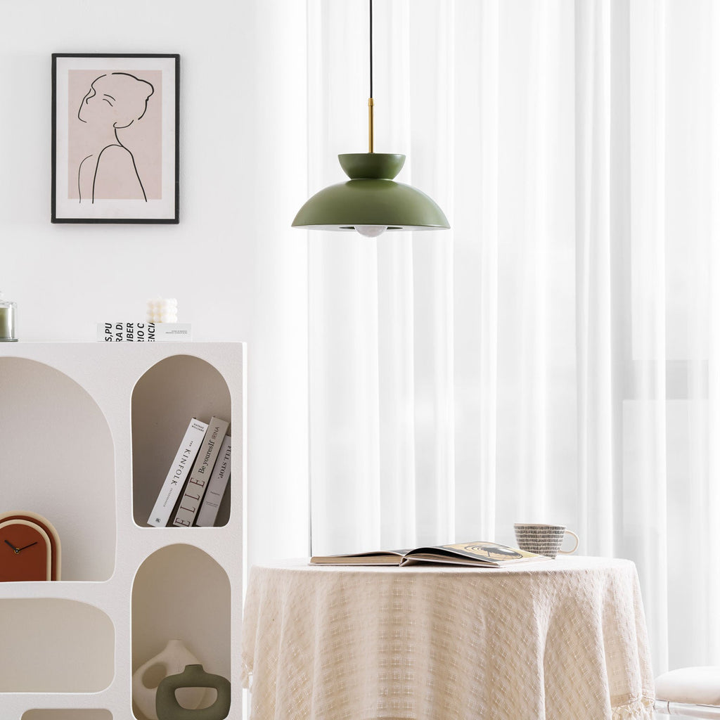 Green Clérachic pendant hung close to a framed print, with a round table with a cream cloth and an open book beneath.