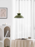 Green dome pendant from Clérachic lit from within, in a white room with a draped table and an open book below.