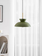 Cropped view of the green Clérachic pendant against white curtains, with the brass stem and an arched shelf at the edge.