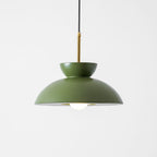 Head-on view of this green Clérachic pendant, with its matte dome, brass stem and round opal bulb on a pale backdrop.