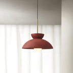 Red dome pendant from Clérachic with a matte, slightly textured finish, hung in front of soft white curtains.