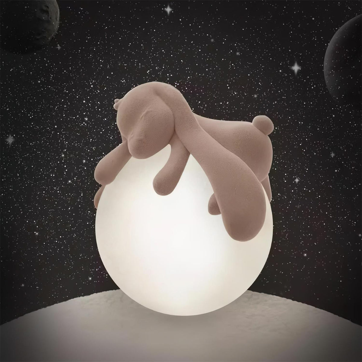 A glowing Clérachic rabbit lamp sits on a grey ledge against a starry night-sky backdrop.
