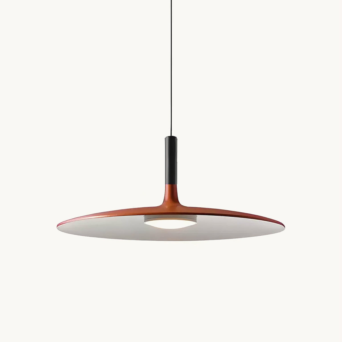 Orange Clérachic pendant light on a plain white backdrop, with a wide flat disc shade, a black stem and a round light below.