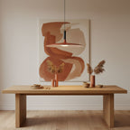Clérachic orange pendant light above a pale oak table, with a rust-toned abstract painting and dried grasses behind.