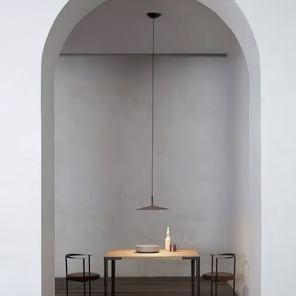 Single Clérachic pendant light hung in a plastered arch, above a small wooden table with two black chairs.