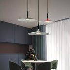 Three Clérachic pendants in grey and orange hung together in a dark dining room with blue-grey cabinets and green chairs.
