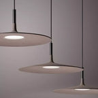 Close view of three overlapping Clérachic disc pendants in taupe, with the round lit diffuser underneath each one.