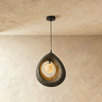 Clérachic dark grey roughcast teardrop pendant with a glowing crater-textured globe inside its open ring, on a black cord.
