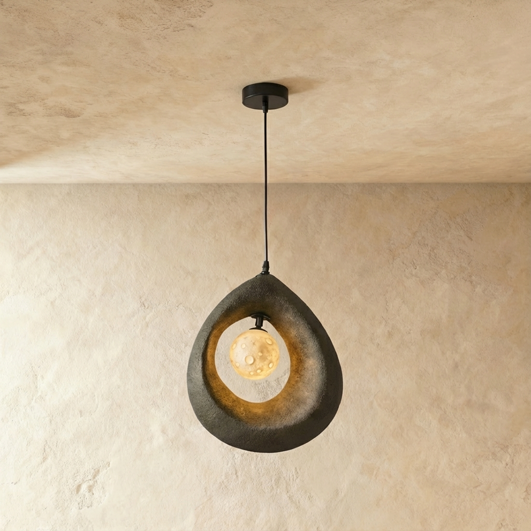 Clérachic dark grey roughcast teardrop pendant with a glowing crater-textured globe inside its open ring, on a black cord.