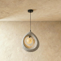 Clérachic light grey roughcast teardrop pendant with a softly lit crater-textured globe inside the ring, on a black cord.