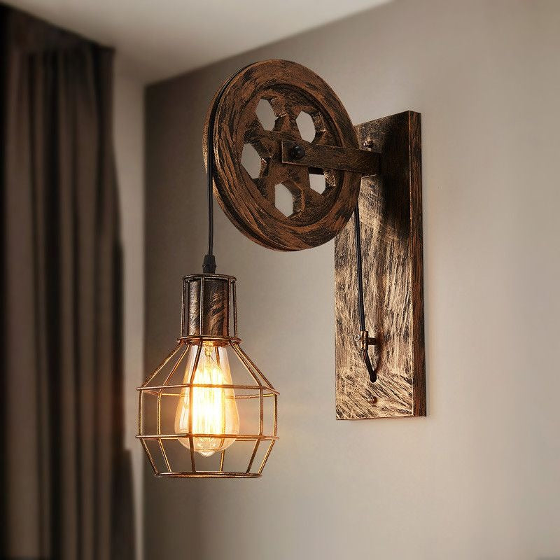 The Clérachic pulley sconce mounted on a beige wall beside a curtain, cage bulb lit warm.