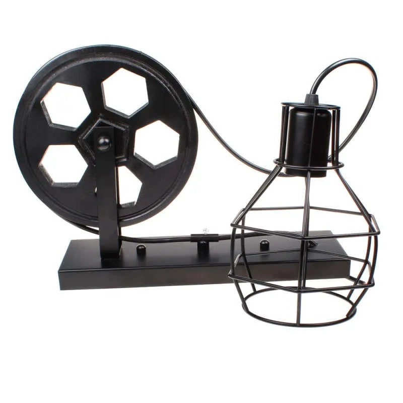 Clérachic pulley sconce in black finish on white, iron wheel feeding cord to the caged bulb.