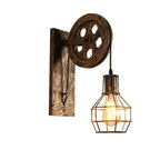 Clérachic pulley sconce angled on white, wood-grain plate and lit cage bulb in view.