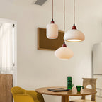 Clérachic Ribbed Ceramic Pendant Light as a three-light cluster — cylinder, dome and ellipse at staggered drops over a round table.
