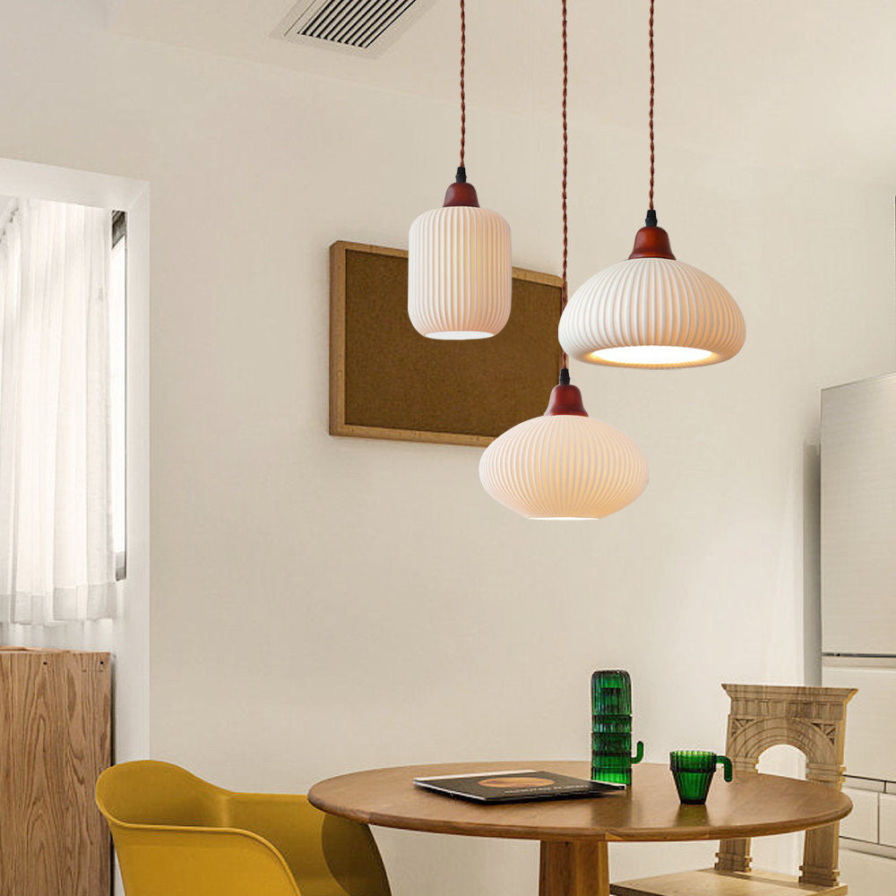 Clérachic Ribbed Ceramic Pendant Light as a three-light cluster — cylinder, dome and ellipse at staggered drops over a round table.