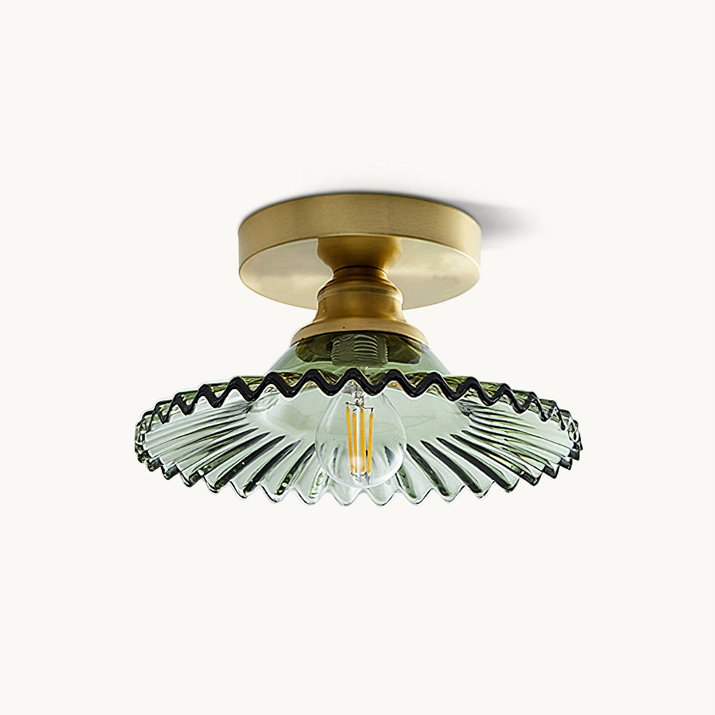 This Clérachic flush ceiling light on a plain backdrop, with a gold canopy and a green ribbed glass shade with a wavy edge.