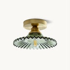 This Clérachic flush ceiling light on a plain backdrop, with a gold canopy and a green ribbed glass shade with a wavy edge.