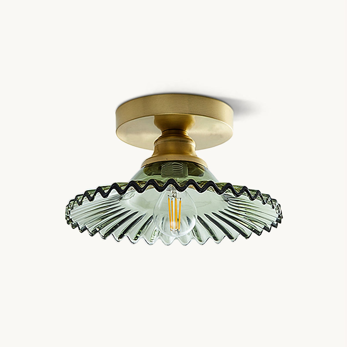 This Clérachic flush ceiling light on a plain backdrop, with a gold canopy and a green ribbed glass shade with a wavy edge.