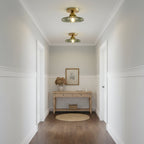 Two green ribbed glass Clérachic ceiling lights lit along a white panelled hallway, with a pale wood console at the far end.