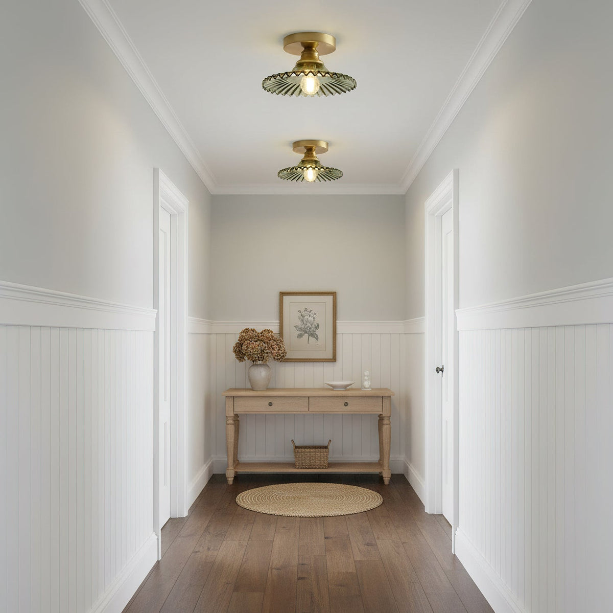 Two green ribbed glass Clérachic ceiling lights lit along a white panelled hallway, with a pale wood console at the far end.