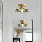 Two green ribbed Clérachic flush lights seen from below, their gold canopies set against a white ceiling above a bright hallway.