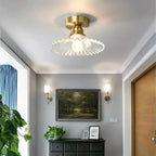 Clear ribbed glass Clérachic flush light lit above a grey hallway, with a dark chest of drawers and a landscape painting below.