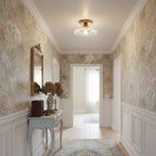 A clear glass Clérachic flush light in a hallway papered in a faded floral pattern, with a pale blue console table beneath.