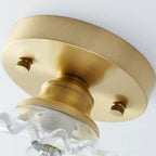 Close view from below of the gold canopy and two knurled screws on this Clérachic ceiling light, with the glass shade edge below.