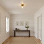 Clear ribbed glass Clérachic ceiling light above a white-panelled hallway with a dark console and three small framed prints.