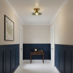 Green glass Clérachic flush light above a hallway with navy panelling, a small desk and a framed map on the wall.