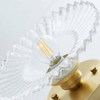 Close view up into the clear ribbed glass shade of this Clérachic ceiling light, showing the filament bulb and gold canopy.
