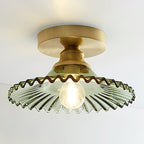 Lit Clérachic ceiling light with a green ribbed glass shade and a warm filament bulb under a gold canopy.