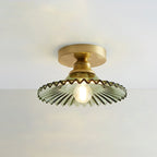 Green glass Clérachic ceiling light lit against a pale grey ceiling, with its gold canopy sitting close to the surface.