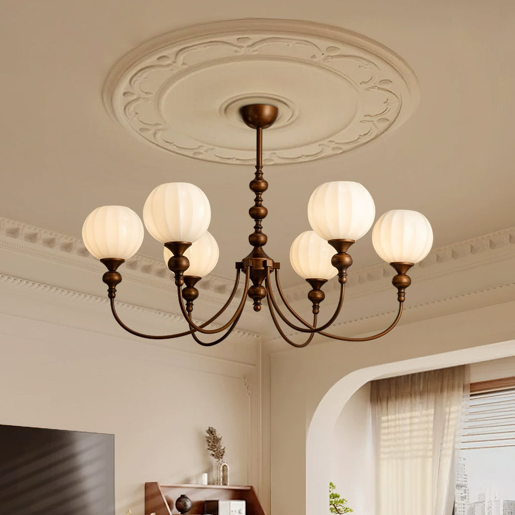 This Clérachic chandelier hangs beneath a moulded ceiling rose, its six ribbed white globes lit against a cream wall and sheer curtains.
