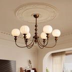 Looking up at this Clérachic chandelier and its ornate plaster ceiling rose, with six ribbed globes glowing on curved bronze arms.