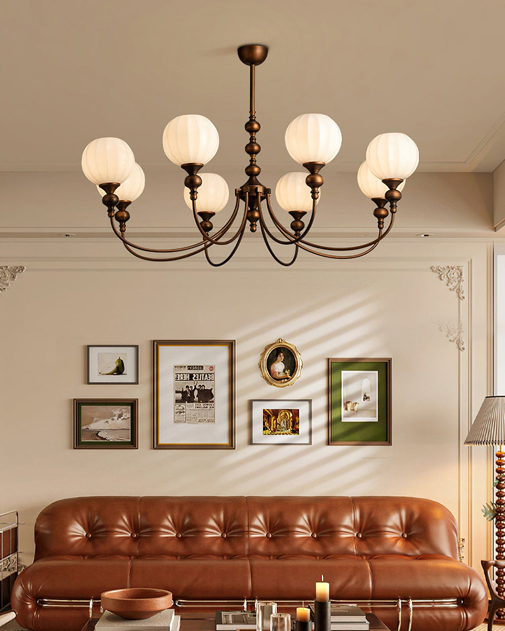 An eight-light Clérachic chandelier with ribbed globes and bronze arms, hung above a buttoned tan leather sofa and a framed picture wall.