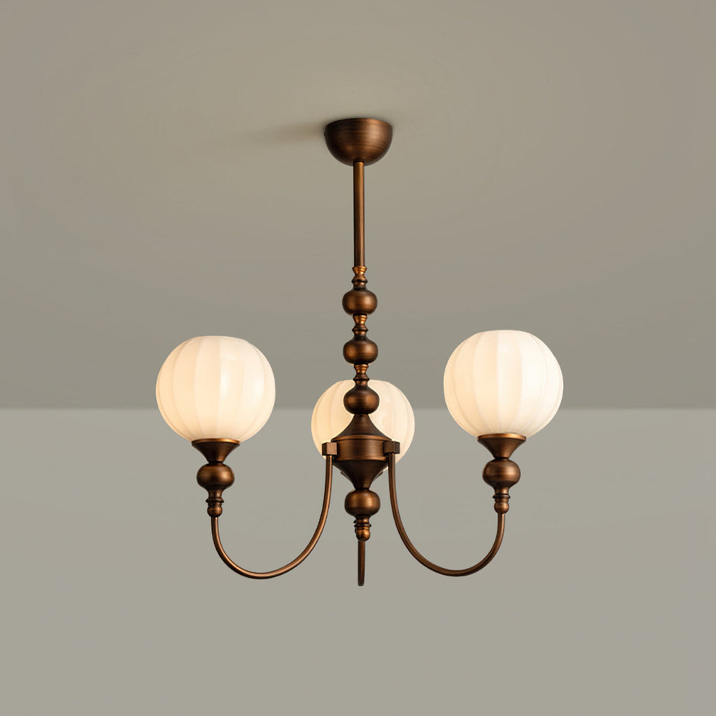 Three-light Clérachic chandelier with ribbed white globes on a turned bronze stem, against a grey backdrop.