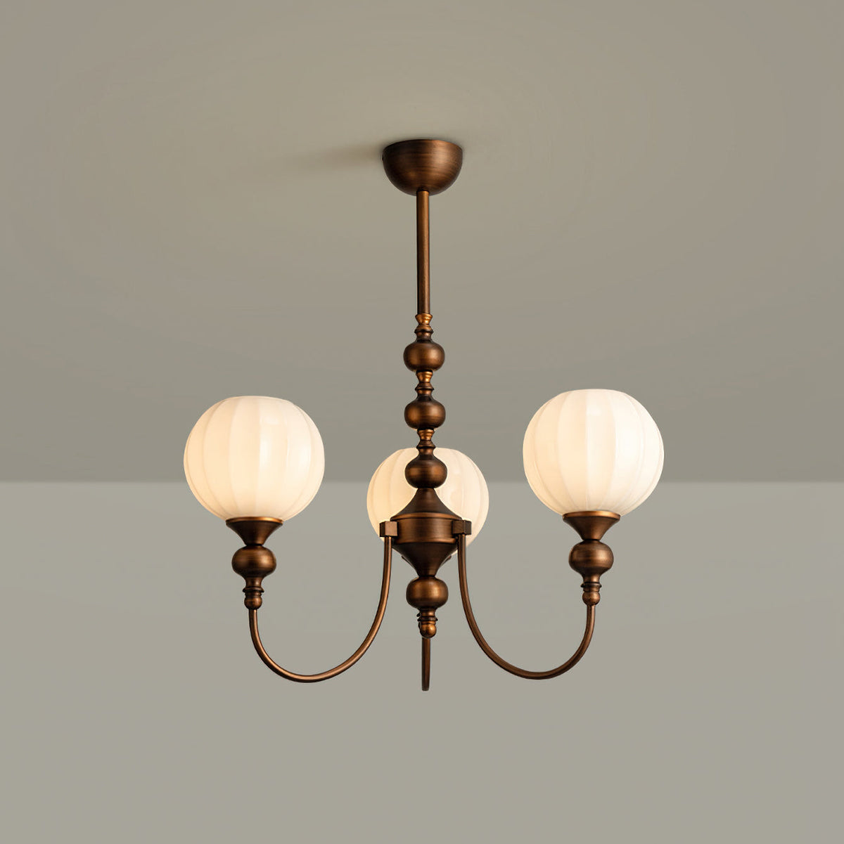 Three-light Clérachic chandelier with ribbed white globes on a turned bronze stem, against a grey backdrop.
