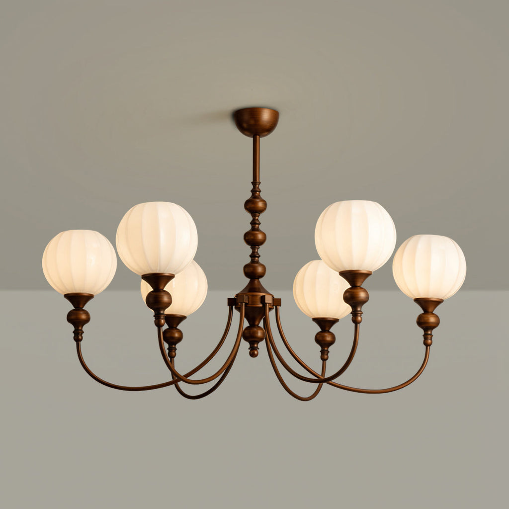 A six-light Clérachic chandelier with ribbed glass globes and arched bronze arms, lit against a grey wall.