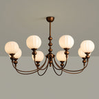 This Clérachic chandelier lit on a grey backdrop, six ribbed globes glowing warm white above the curved bronze arms.