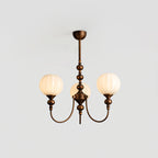 A three-light Clérachic chandelier lit with ribbed globes glowing warm, hung from a short bronze stem against a pale grey ceiling.
