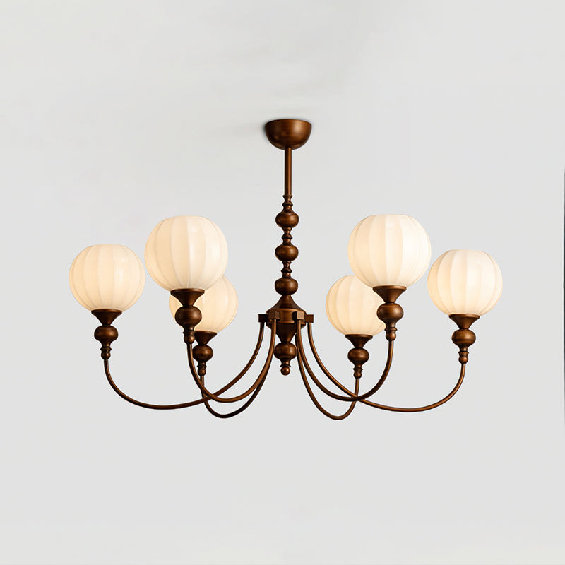 Six-light Clérachic chandelier lit against a pale grey ceiling, its ribbed white globes glowing softly above the bronze arms.
