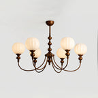 Six-light Clérachic chandelier lit against a pale grey ceiling, its ribbed white globes glowing softly above the bronze arms.